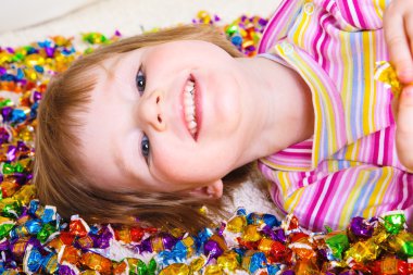 Kid lying among candies clipart