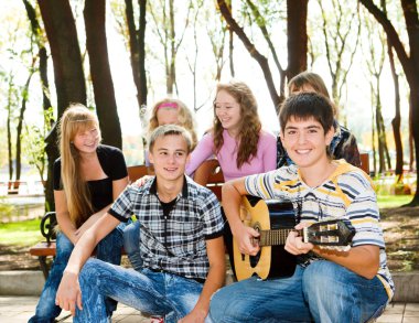 Teens crowd in park clipart