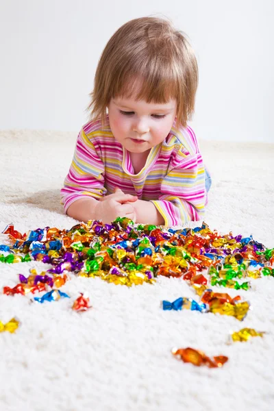 Маленькая девочка смотрит на конфеты — стоковое фото