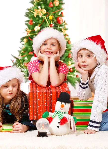 Kinder sitzen neben Weihnachtsgeschenken — Stockfoto