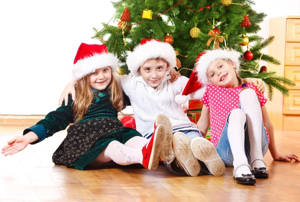 Kinderen in santa hoeden omarmen — Stockfoto