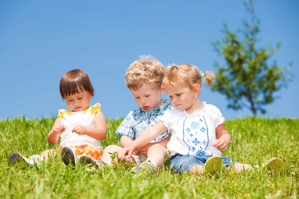 Los niños se sientan en la hierba —  Fotos de Stock