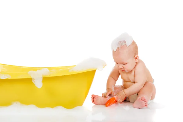 Bebê senta ao lado do banho — Fotografia de Stock