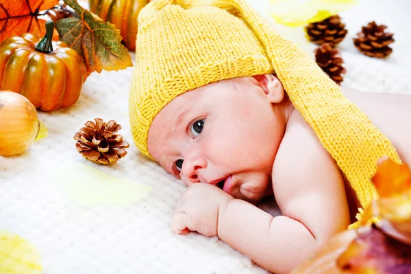 Младенец среди осенних листьев и тыкв — стоковое фото