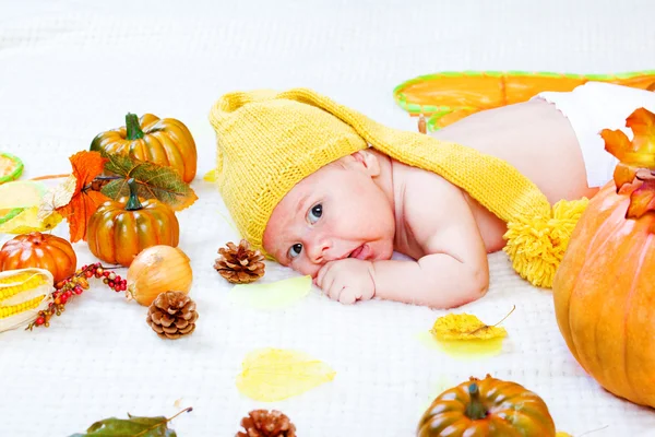 Bebê entre folhas e legumes — Fotografia de Stock