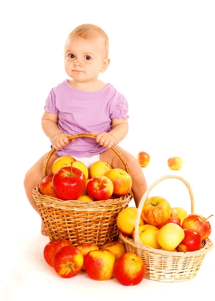 Ребенок сидит на корзине яблок — стоковое фото