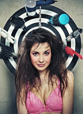 Cute brunette posing as a target with hairdresser's instruments clipart