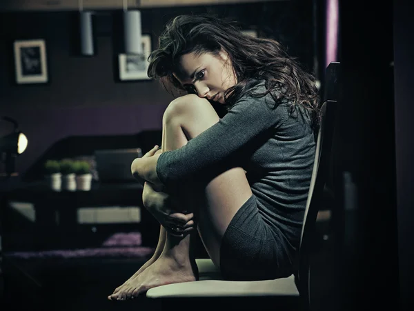 Traurige Frau sitzt auf einem Stuhl — Stockfoto