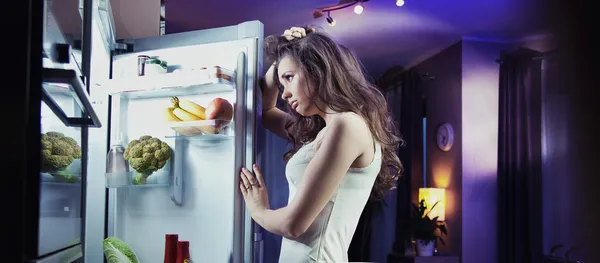 Jeune femme regardant réfrigérateur — Photo