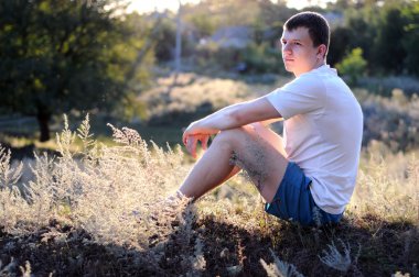 genç adam bir çim üzerinde oturur