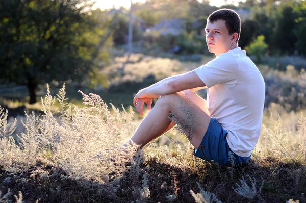 Young guy sits on a grass — Stock Photo, Image
