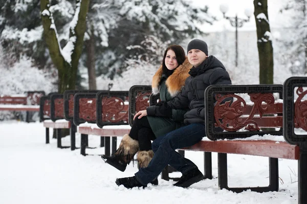 Jovem casal sentado no banco no parque — Fotografia de Stock