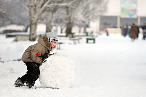 Boy sculpts snowman — Stock Photo, Image