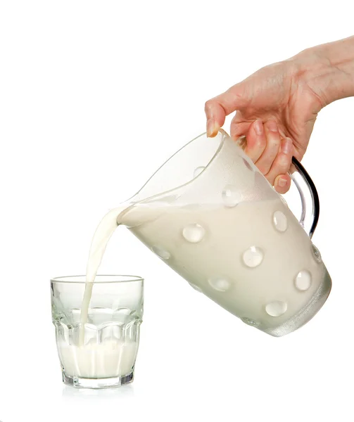Mão derramando leite em vidro — Fotografia de Stock