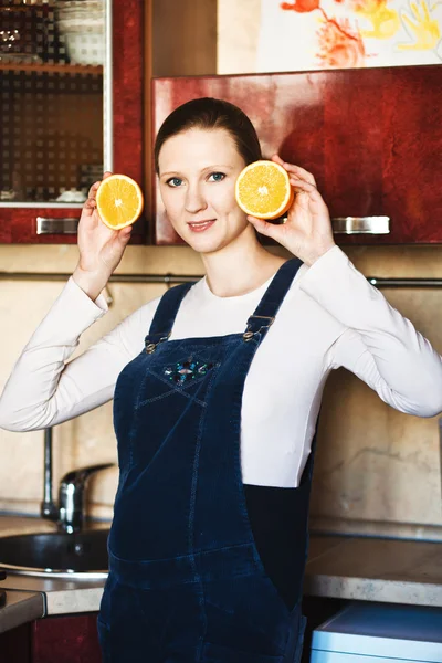 Pregnant woman at kitchen with orange — Stock Photo, Image