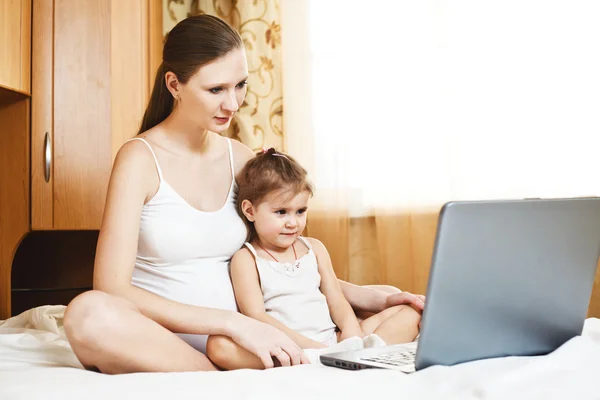 Счастливая беременная мать и ребенок с ноутбуком — стоковое фото