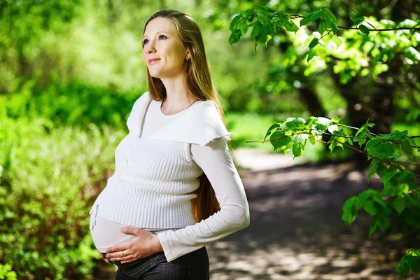Gravid kvinna avkopplande i parken Royaltyfria Stockfoton