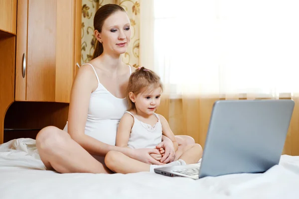 Беременная мать и ребенок с ноутбуком — стоковое фото