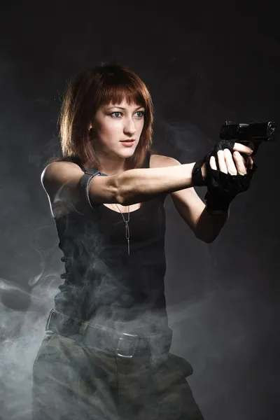 Woman holding gun with smoke — Stock Photo, Image