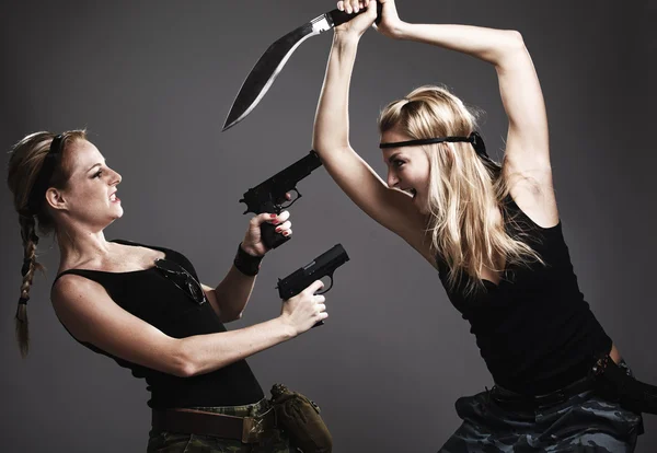 Two sexy women with gun and dagger on gray — Stock Photo, Image