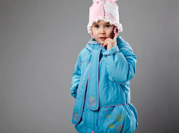 Kleines Mädchen auf grau mit Phon — Stockfoto