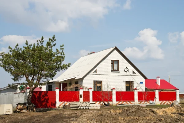 Pequena casa atrás da cerca vermelha — Fotografia de Stock