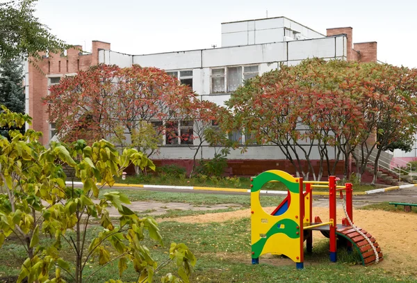 Будівля дитячого садка і фрагмент дитячого майданчика — стокове фото