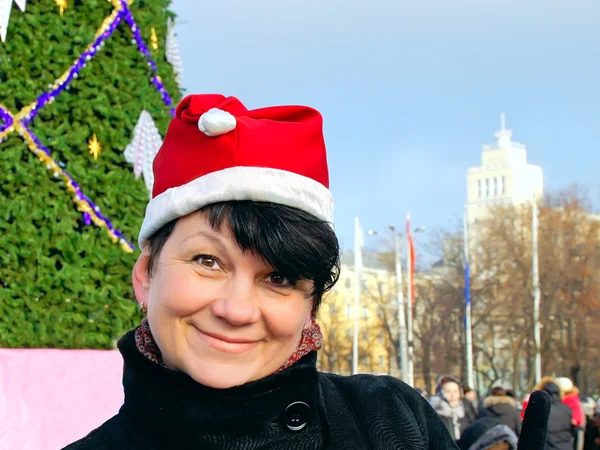 Mujer feliz con gorra Santa Claus cerca del árbol de Año Nuevo —  Fotos de Stock