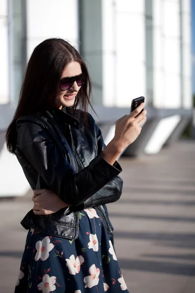 Женщина в солнечных очках смотрит в телефон — стоковое фото