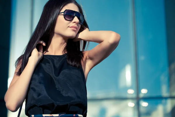 Женщина в солнечных очках на стеклянной стене — стоковое фото