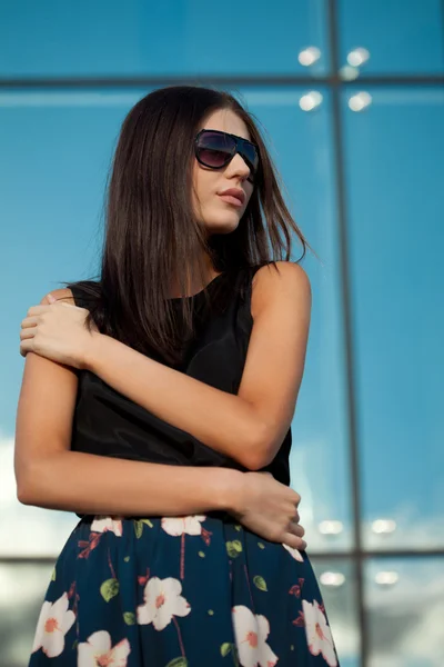 Žena nosí sluneční brýle přes skleněnou zeď — Stock fotografie