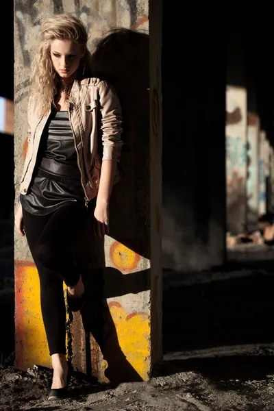 Woman standing near column wearing leather jacket — Stock Photo, Image