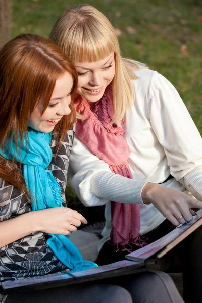 Two laughing sisters with photo album in the park — Stock Photo, Image