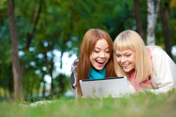 Två skrattande systrar med laptop i parken — Stockfoto