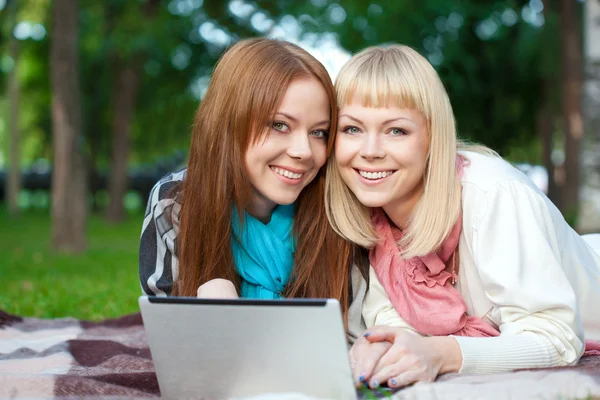 Twee zusters met laptop in het park — Stockfoto