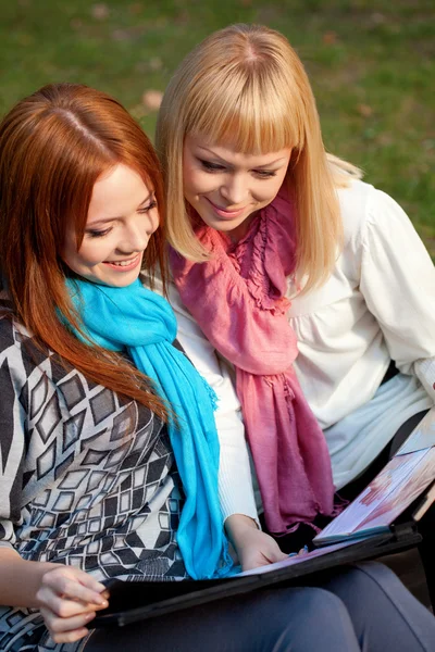 Two sisters with photo album in the park — Stock Photo, Image