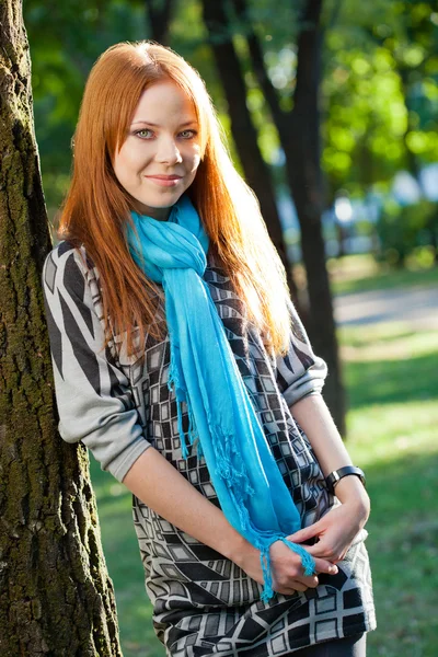 Mujer de pelo rojo sonriente cerca del árbol — Foto de Stock