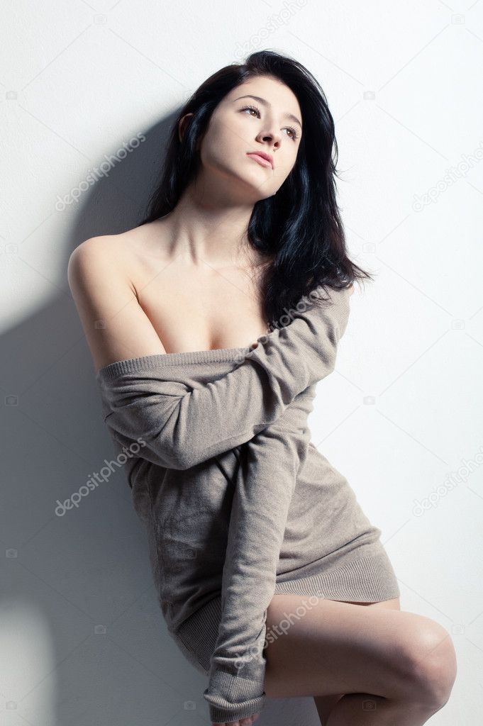Woman posing at studio near wall, looking up