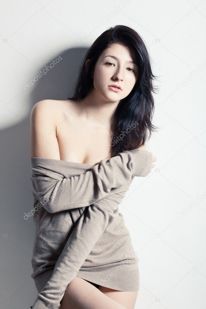 Woman posing at studio near wall, looking at camera