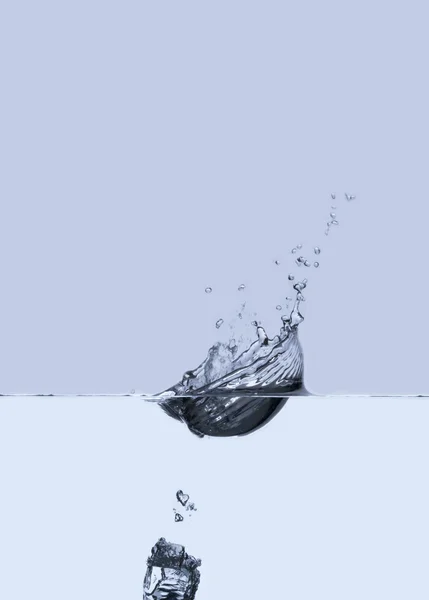 Ледяной куб падает в воду — стоковое фото
