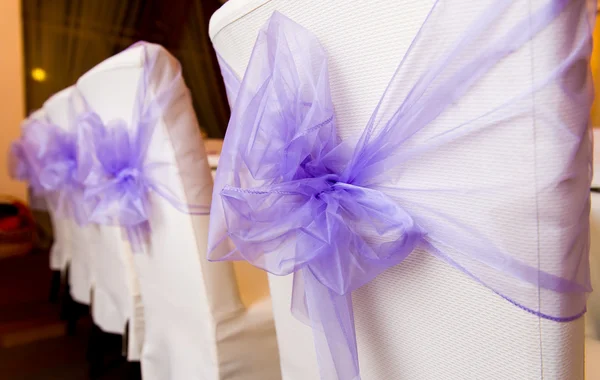 Sillas de boda blancas decoradas con lazos púrpura —  Fotos de Stock