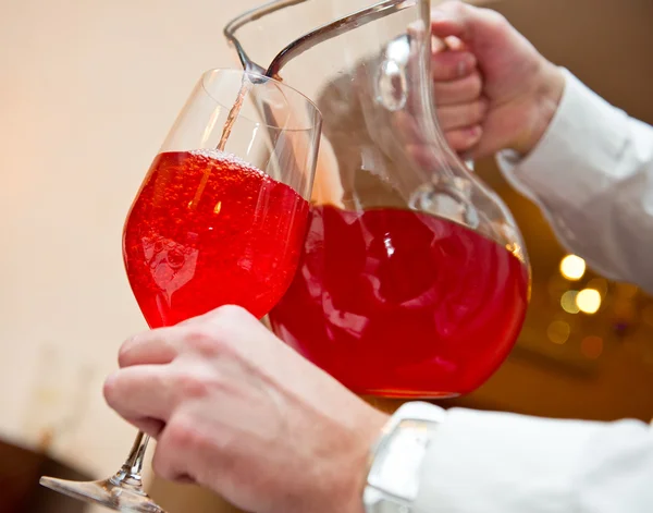 Servitören hälla kompott från jug i ett glas — Stockfoto