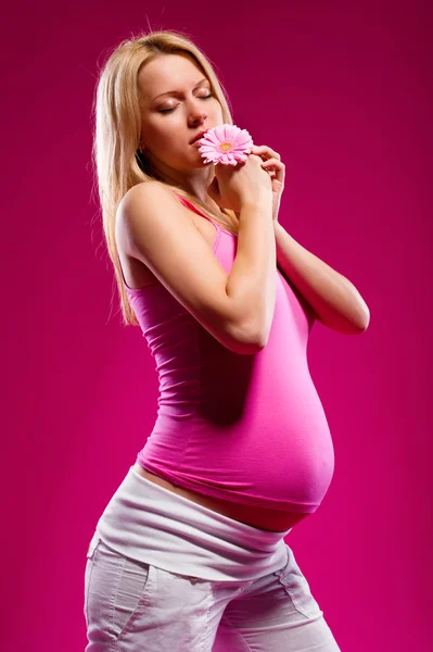妊娠中の若い女性の花を持つ — ストック写真