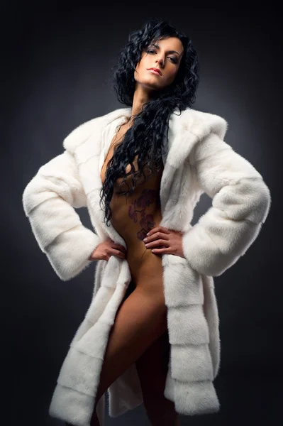Gorgeous sexy brunette wearing white fur coat posing indoors — Stock Photo, Image