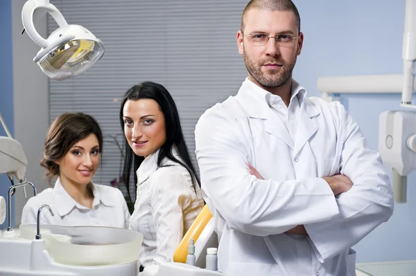 Friendly male dentist, assistant and smiling patient at dental clinic — Stock Photo, Image