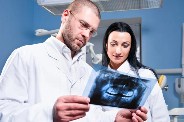 Zubař a asistent kontrolu x-ray na zubní klinice — Stock fotografie