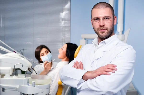 Dentista masculino amigável com assistente e paciente na clínica odontológica — Fotografia de Stock