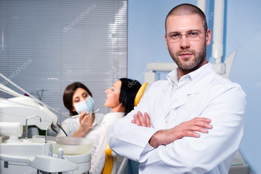 Friendly male dentist with assistant and patient at dental clinic