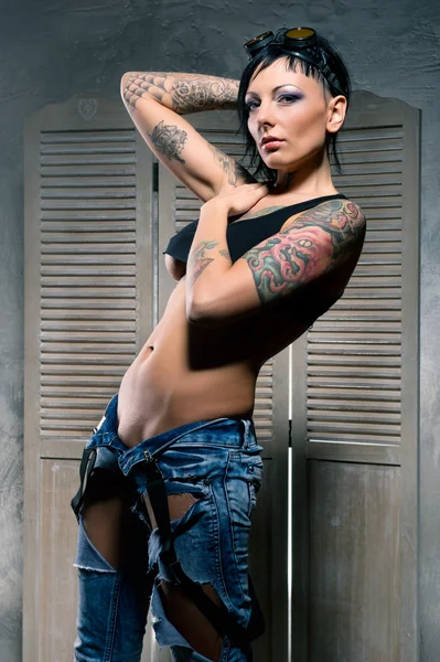 Красивая женщина со множеством татуировок, позирующих в помещении — стоковое фото