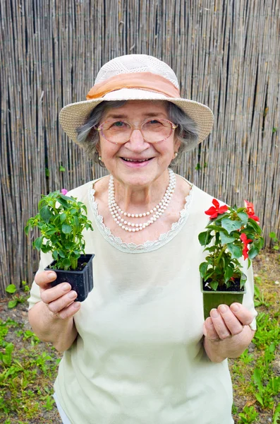 Happy senior kvinna med blommor i trädgården — Stockfoto